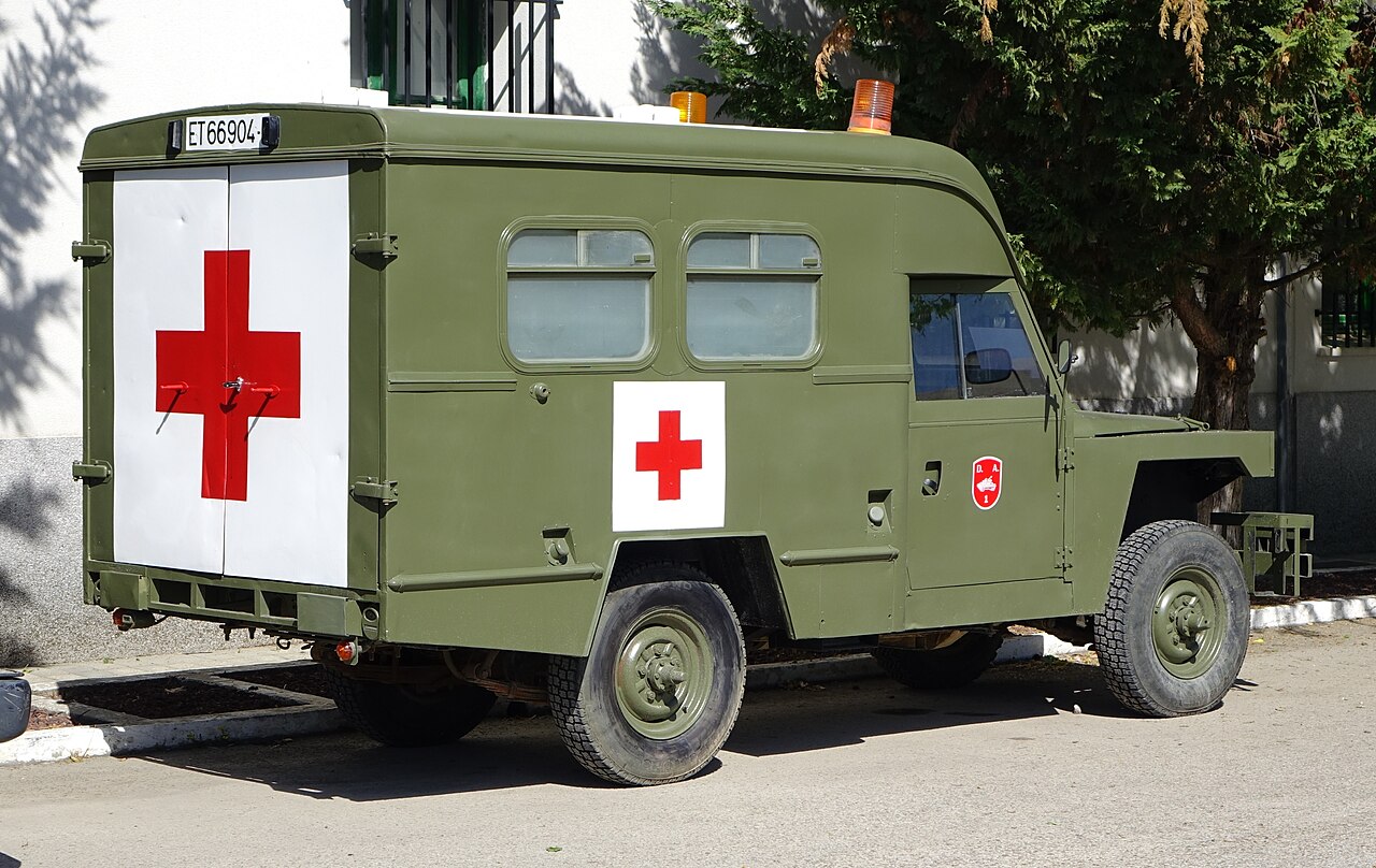 Spanish Army Land Rover Santana 109 ambulance, registration ET 66904 — olive green box body with red cross panels, twin rear doors and amber roof beacons